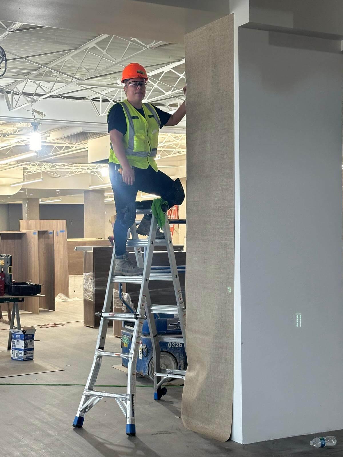 Diamond Wallpaper's owner standing on a ladder installing wallpaper.